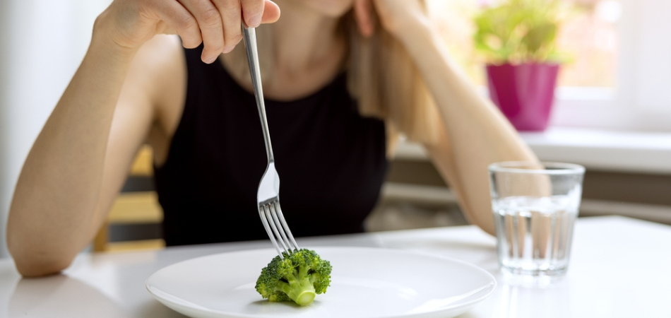 A woman struggling to eat a broccoli