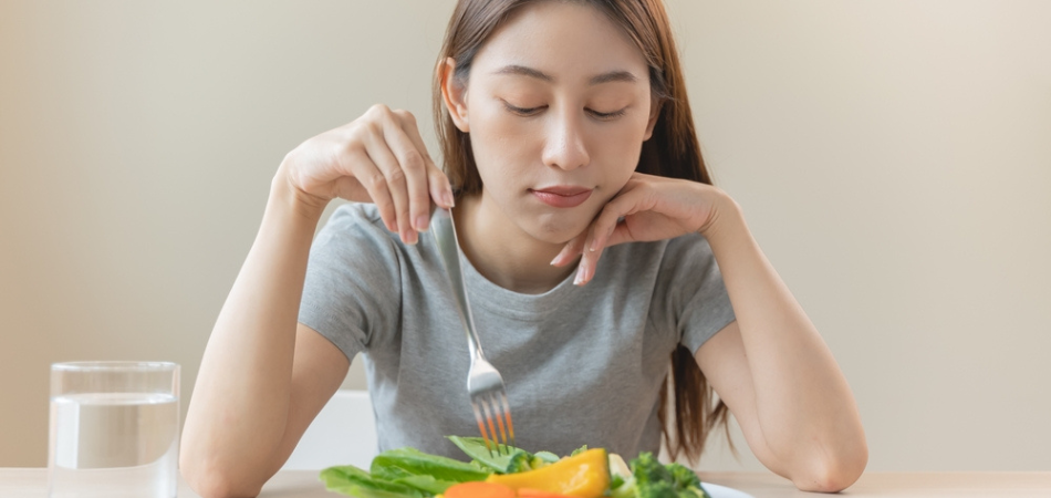 A woman struggling to eat her food because of an eating disorder