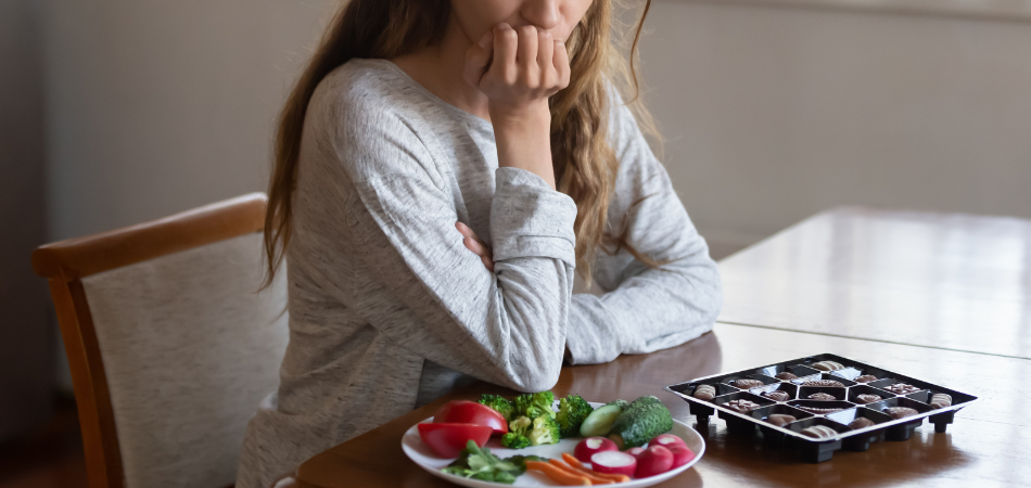 A young woman looking depressed at a plate of food