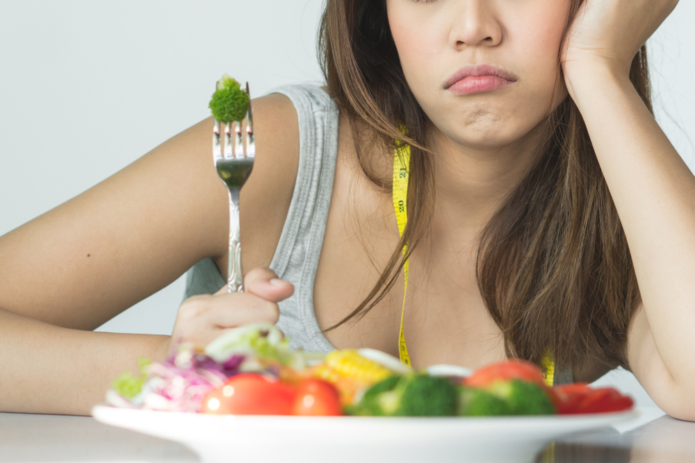 Woman eating veggies in sad