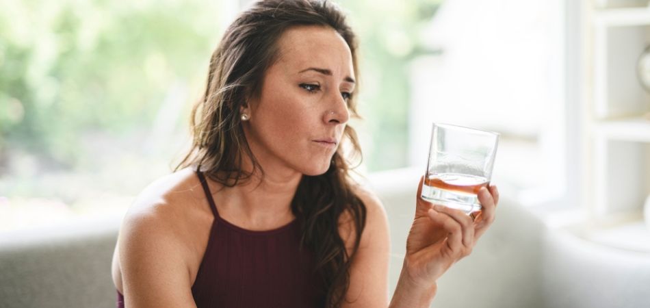 depressed woman looking at alcohol glass