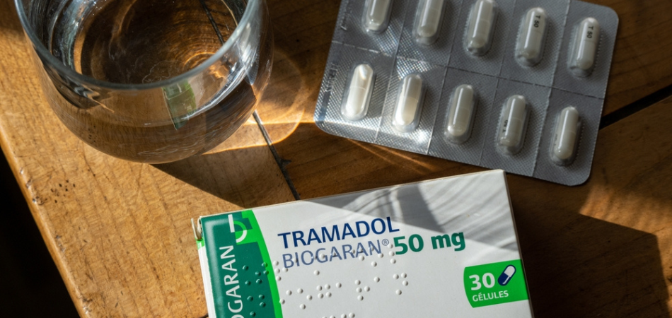 A glass of alcohol and tramadol medication on a table