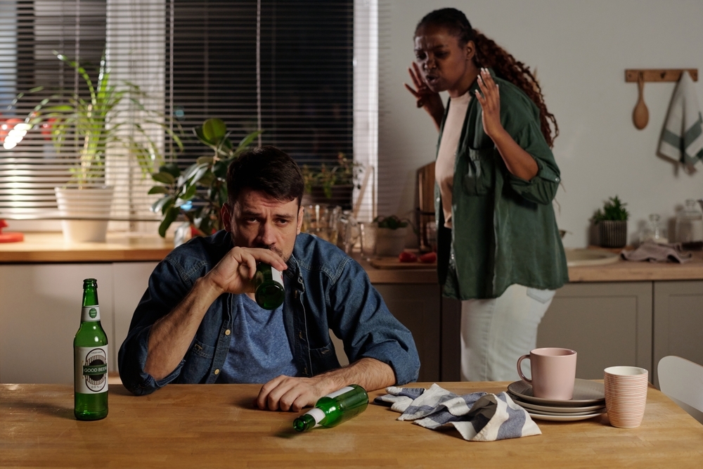 Unhappy man drinking alcohol infront of wife