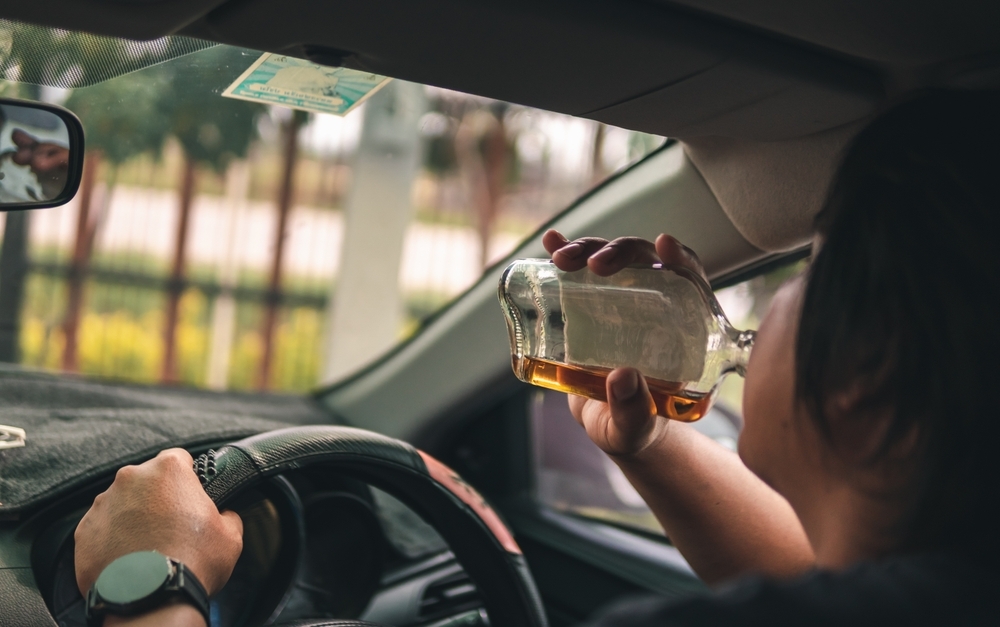 Man drinking alcohol while driving in his car