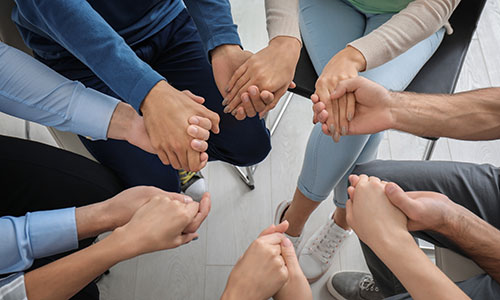 image of people holding hands during a group therapy session